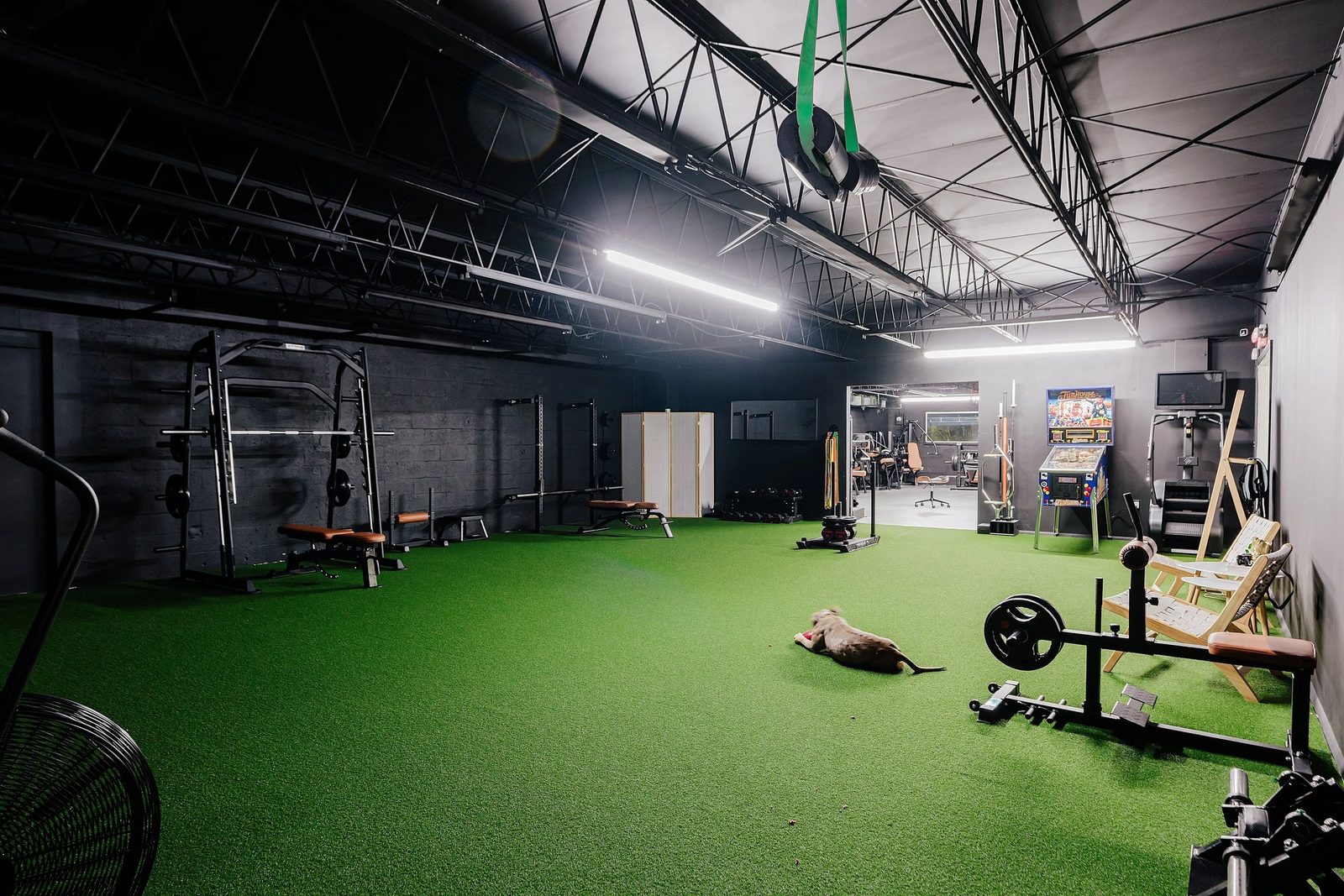 Squat rack and benches on green turf inside The Content Gym, a 3,000 sq ft gym rental studio in Little River, Miami