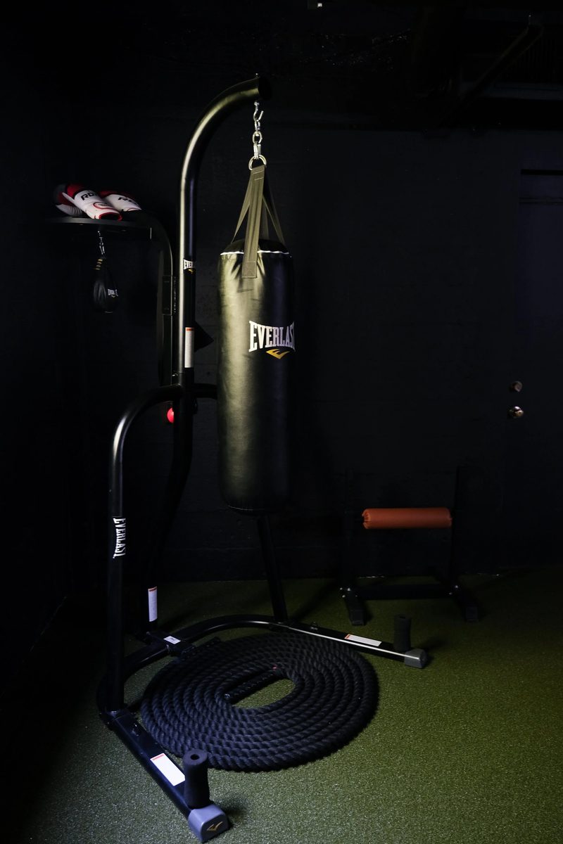 A heavy bag and battle rope in the corner of the turf area