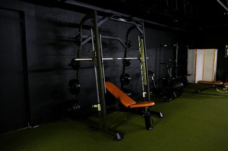 A power rack loaded with plates and an orange bench on turf
